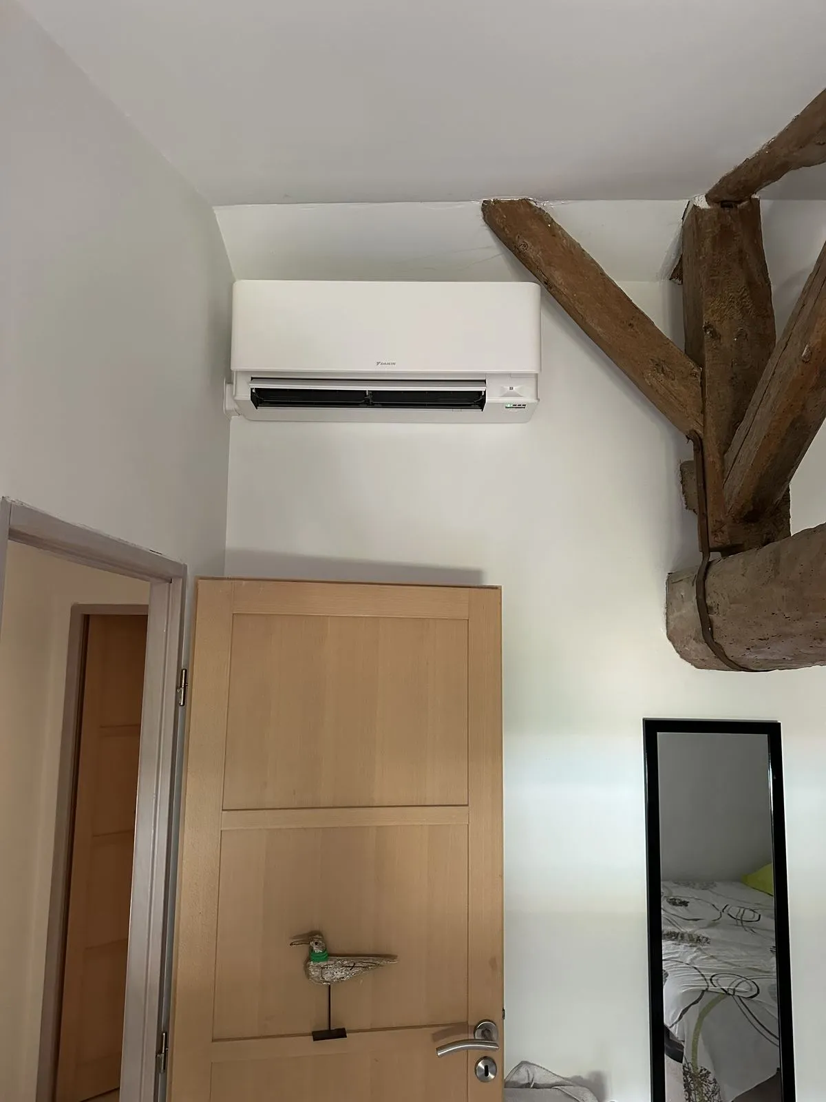 Unité intérieure murale Daikin posée dans une chambre à poutre apparente, chantier climatisation Cornus à Revel