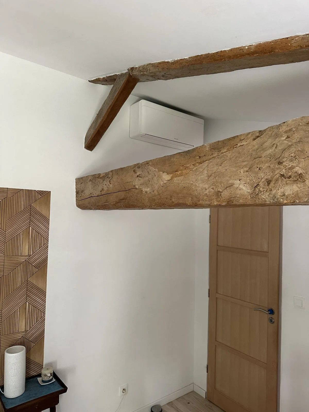 Unité intérieure murale de climatisation réversible Daikin intégrée sous les poutres anciennes d'une maison à Revel, réalisation Cornus