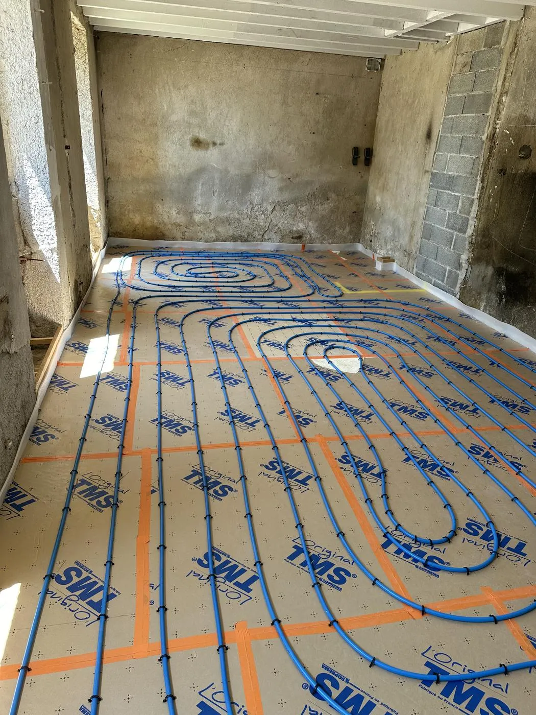 Serpentins de plancher chauffant posés en spirale sur isolant dans une pièce en rénovation à Lavaur, réalisation Cornus